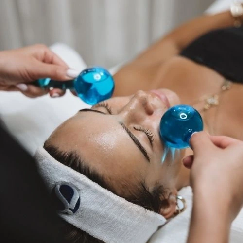 Woman having a facial with a cold globe facial massage add-on