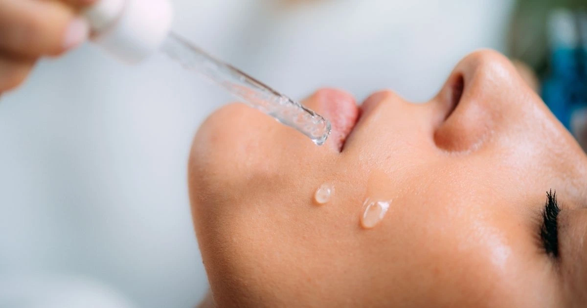 Woman dripping Hyaluronic Acid on her skin.